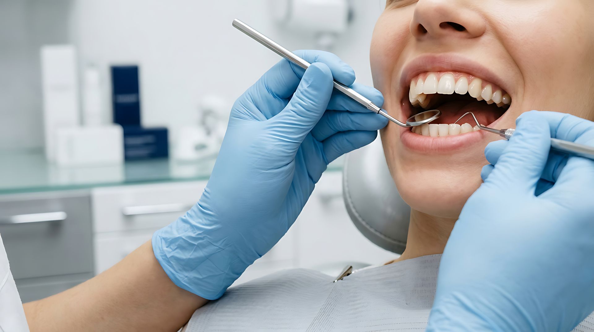Dentist in blue gloves examines a smiling patient's healthy white teeth using a mirror and a probe Dentist in blue gloves examines a smiling patient's healthy white teeth using a mirror and a probe