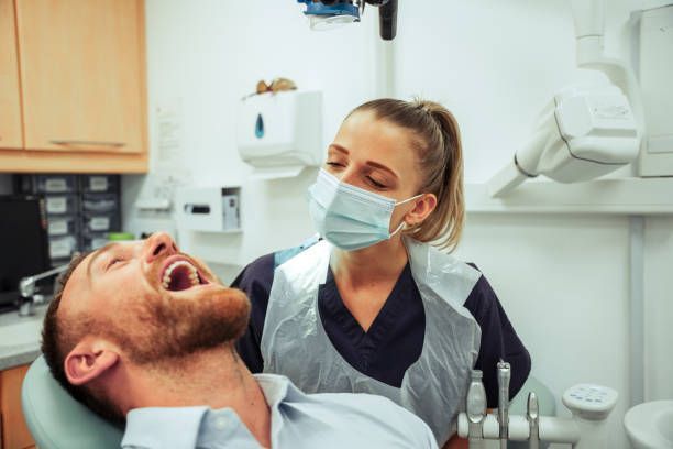 Dental professional examining patient in modern clinic with dental equipment and X-ray machine.