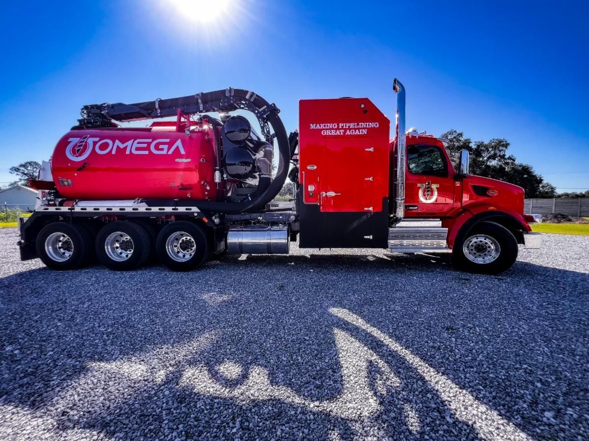 A red omega truck is parked in a gravel lot
