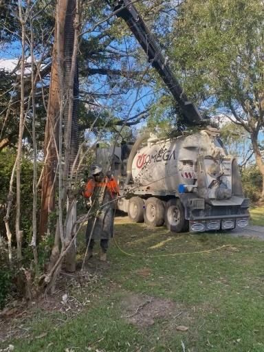 A man is standing next to a vacuum truck in a yard.