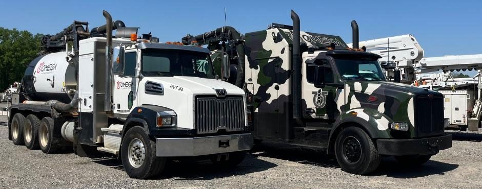 Two trucks are parked next to each other in a gravel lot.