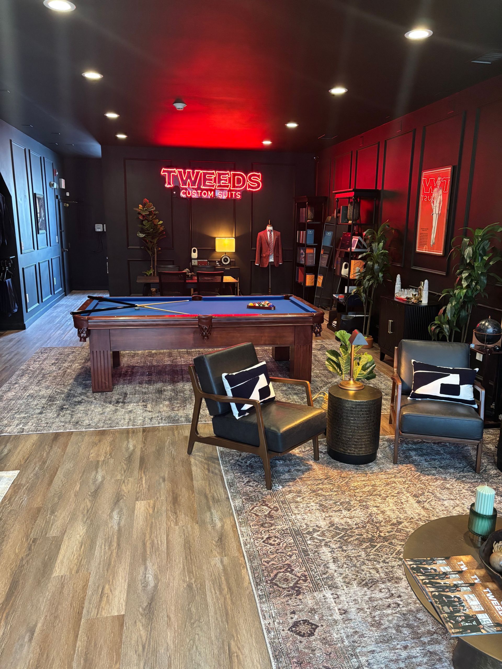 Pool hall with pool table, seating, decor, and a red neon sign.