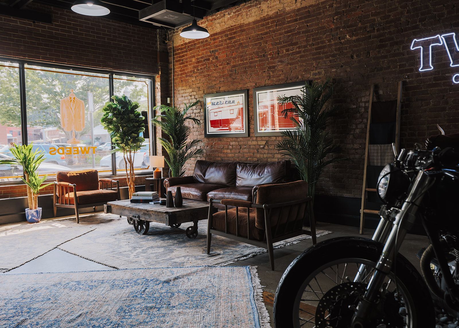 Cozy industrial lounge with leather furniture, brick walls, and a motorcycle.