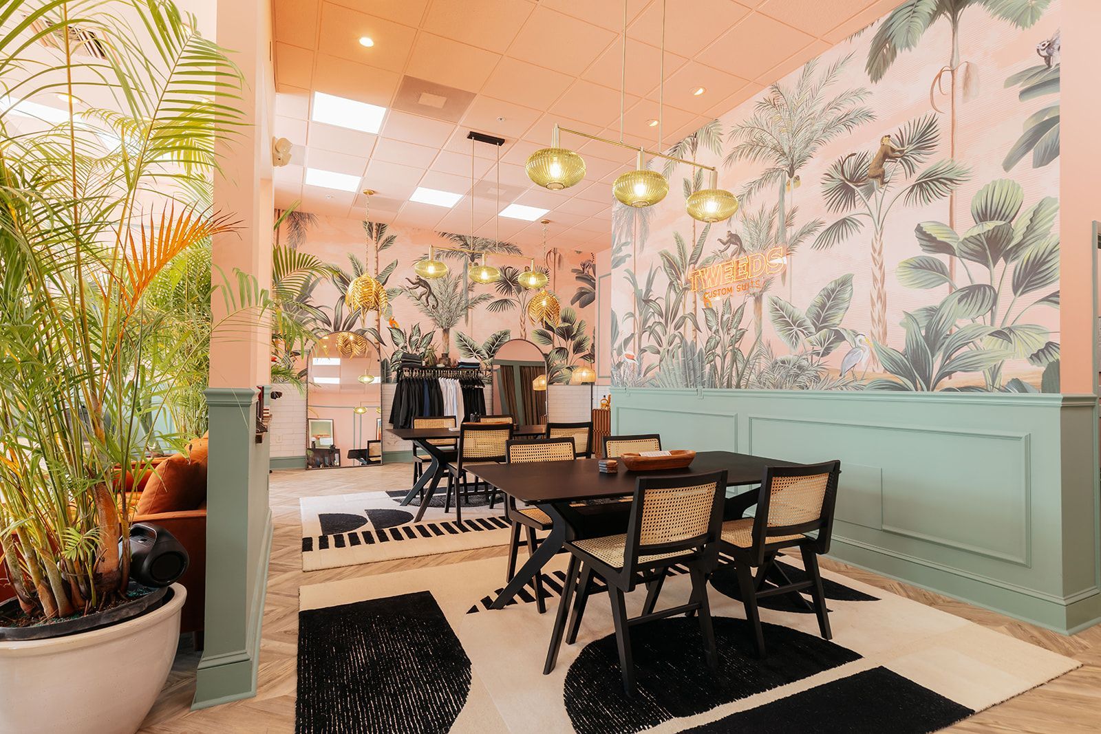 A dining room with tropical wallpaper, black table, and green accents.