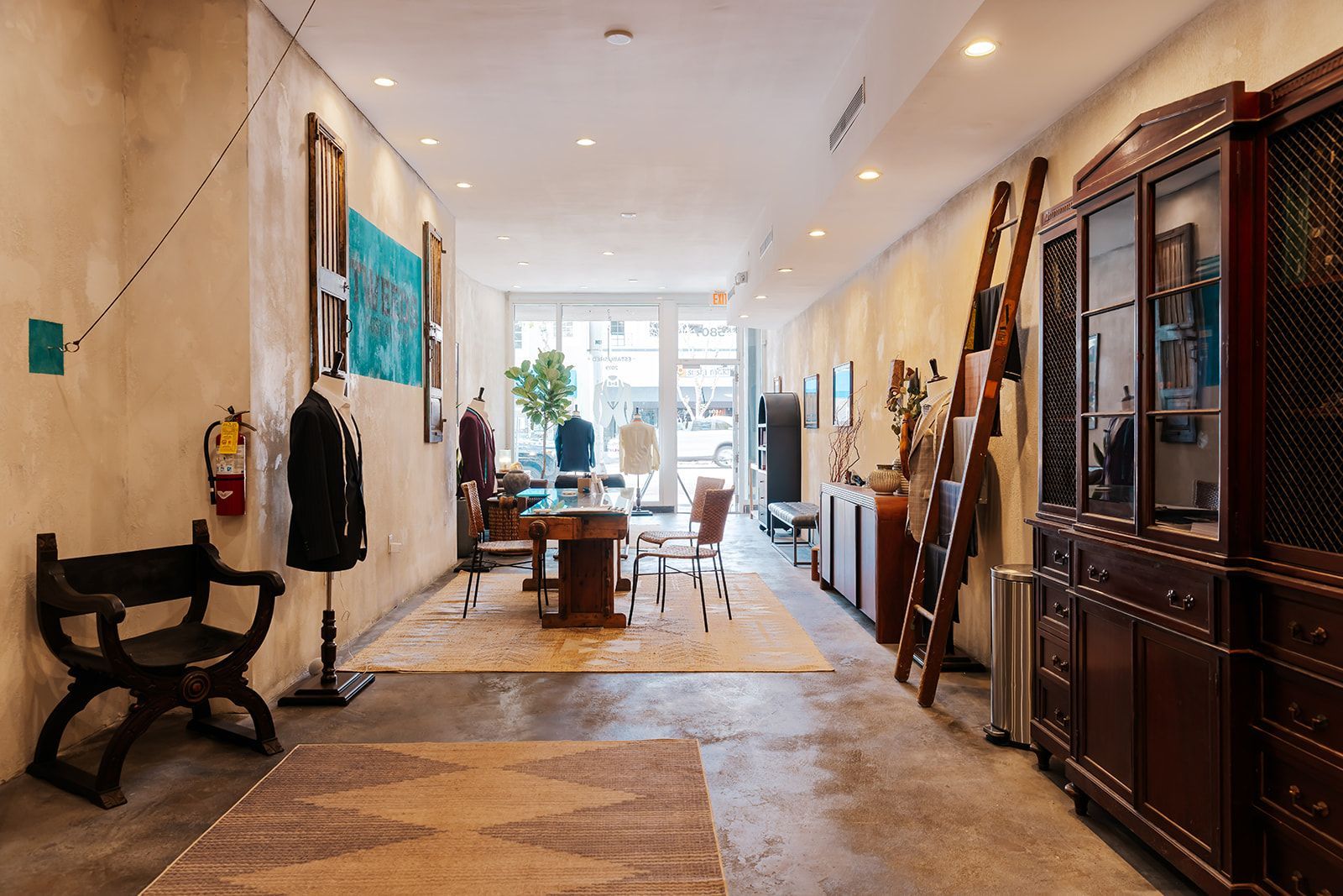 Interior of a shop with vintage furniture, a rug, and art on the walls.