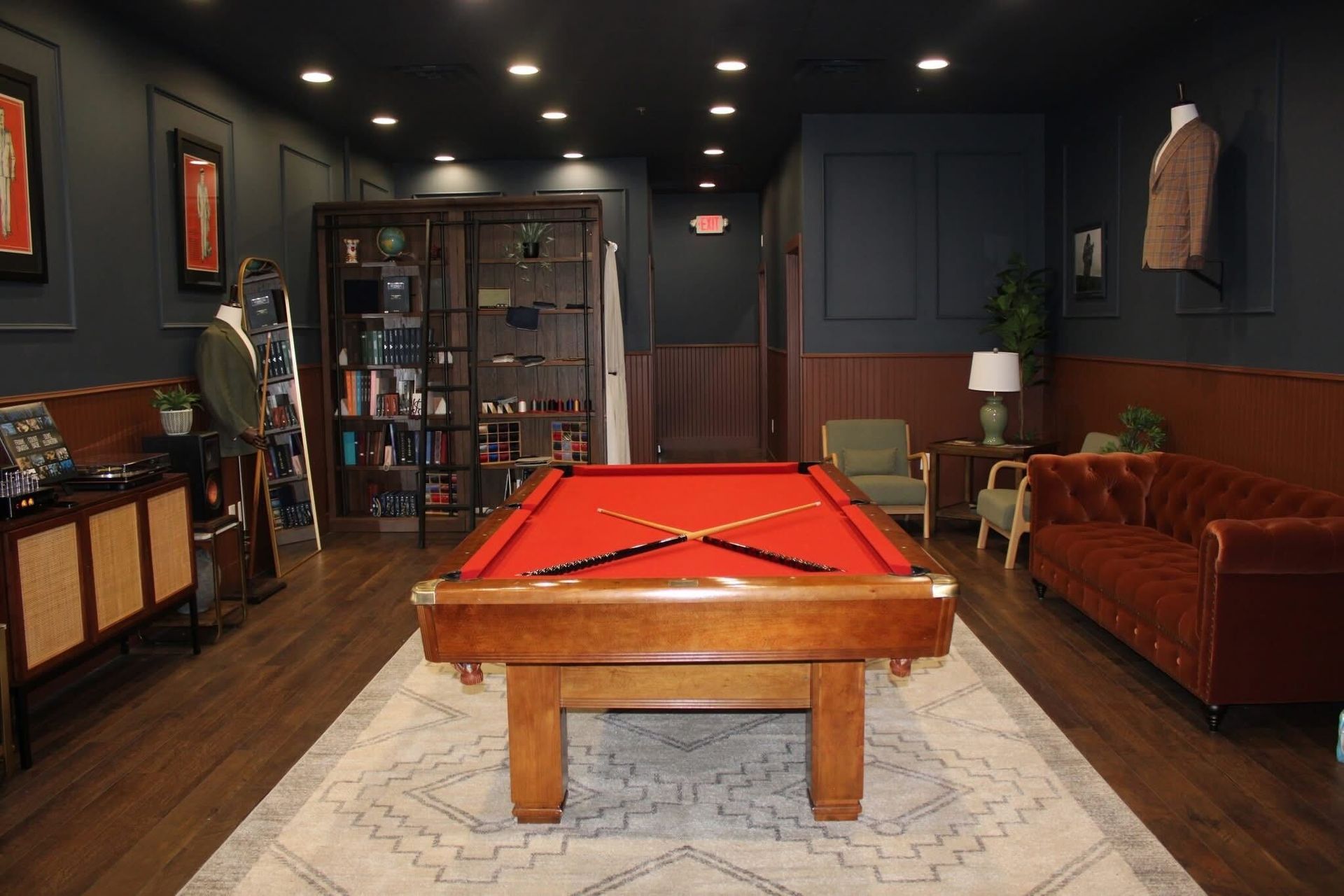 Pool hall with a red felt table, dark walls, and vintage furniture.