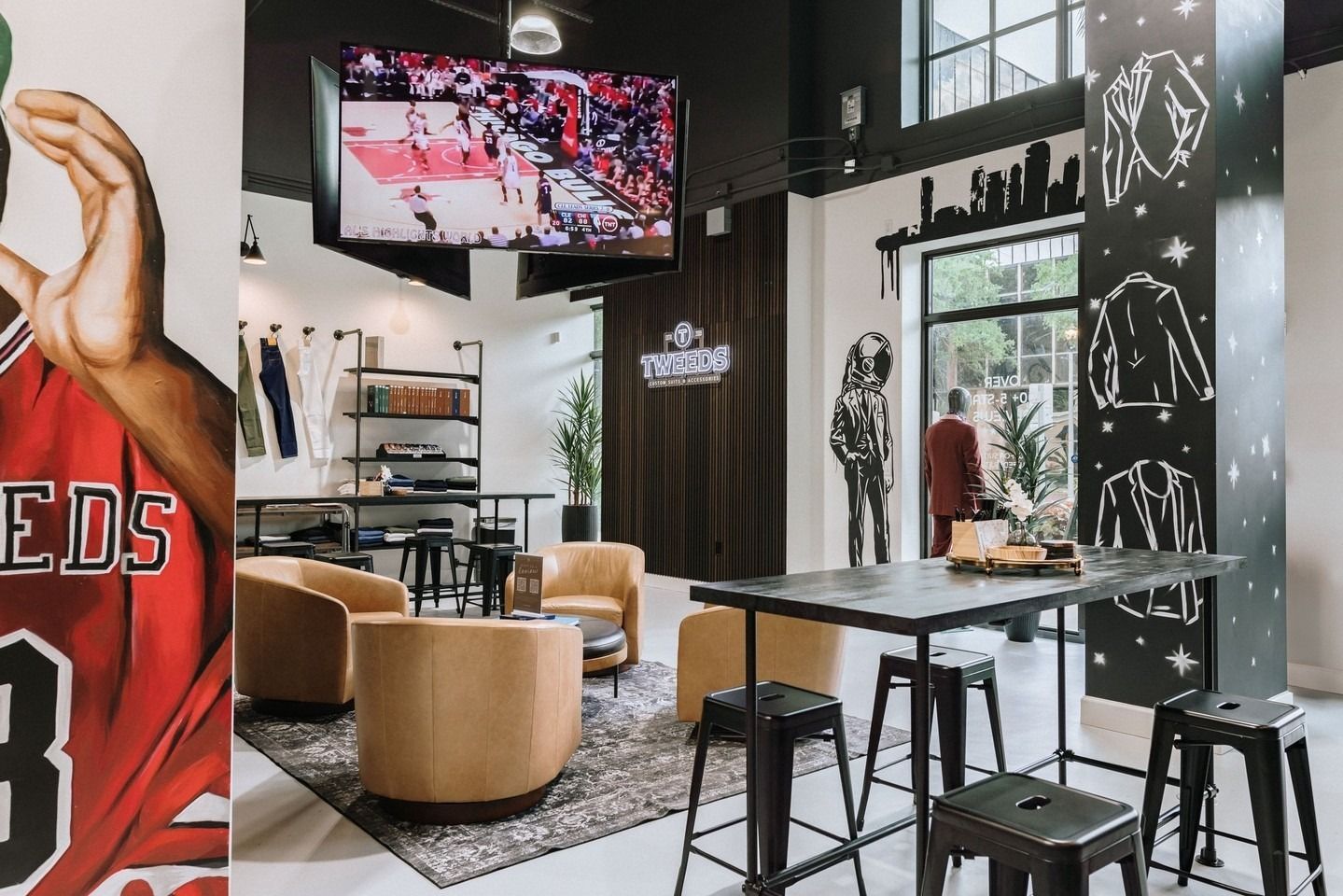 A stylish store interior with seating, a large TV, and apparel displays. Dark furniture, and a Chicago Bulls jersey.