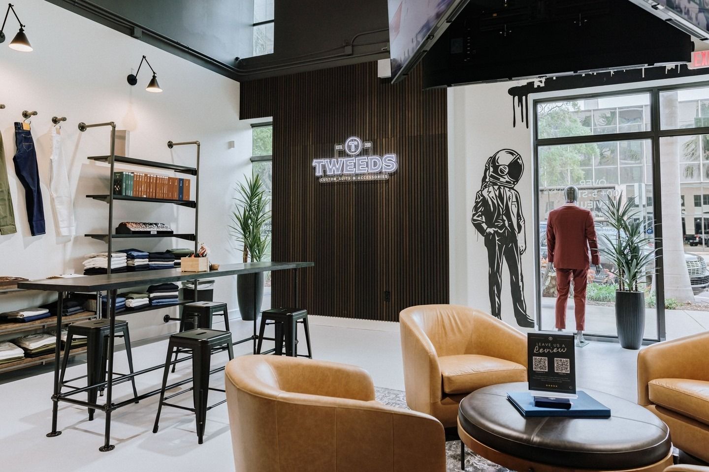 Inside of a clothing store with seating, merchandise, and a mannequin wearing a red suit.