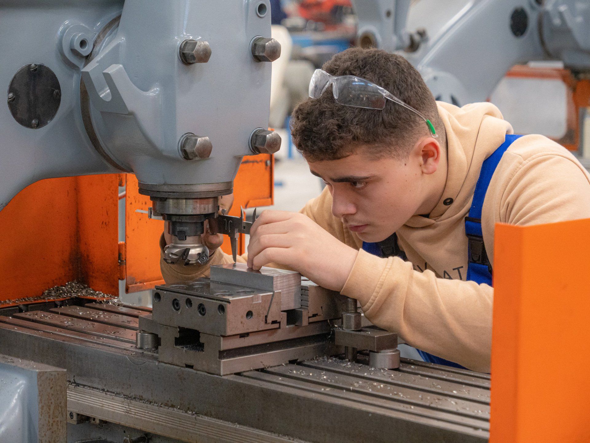 Een jongeman werkt aan een machine in een fabriek.