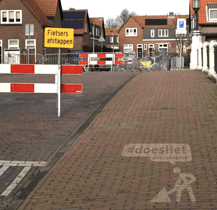Een straat met een geel bord waarop staat fietsers afstappen