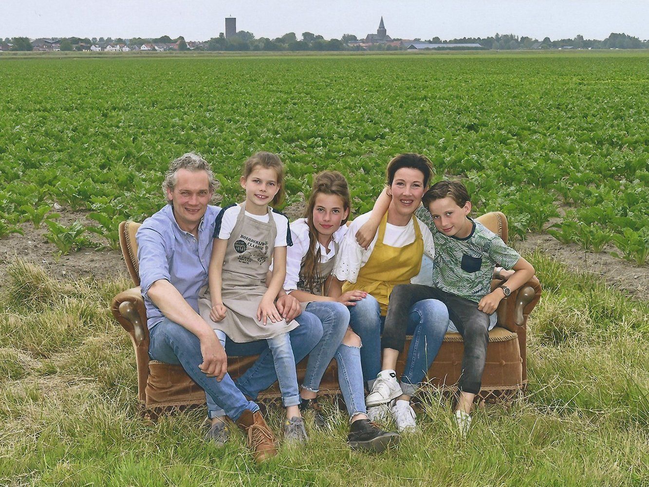 Een gezin zit op een bank in een veld.