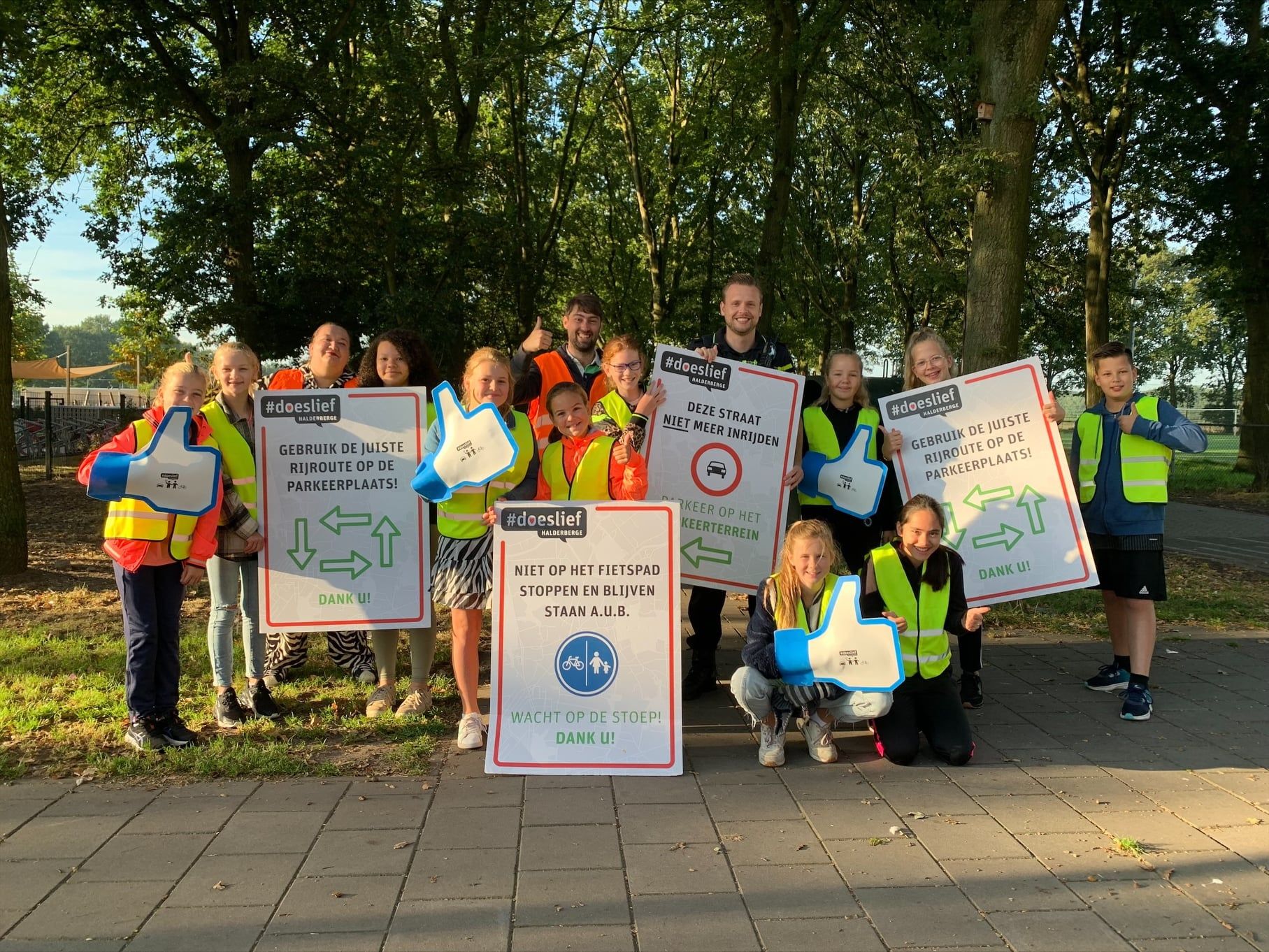 Een groep kinderen poseert voor een foto terwijl ze borden vasthouden.
