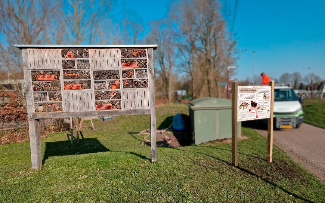 Een groot houten bord staat midden in een grasveld.