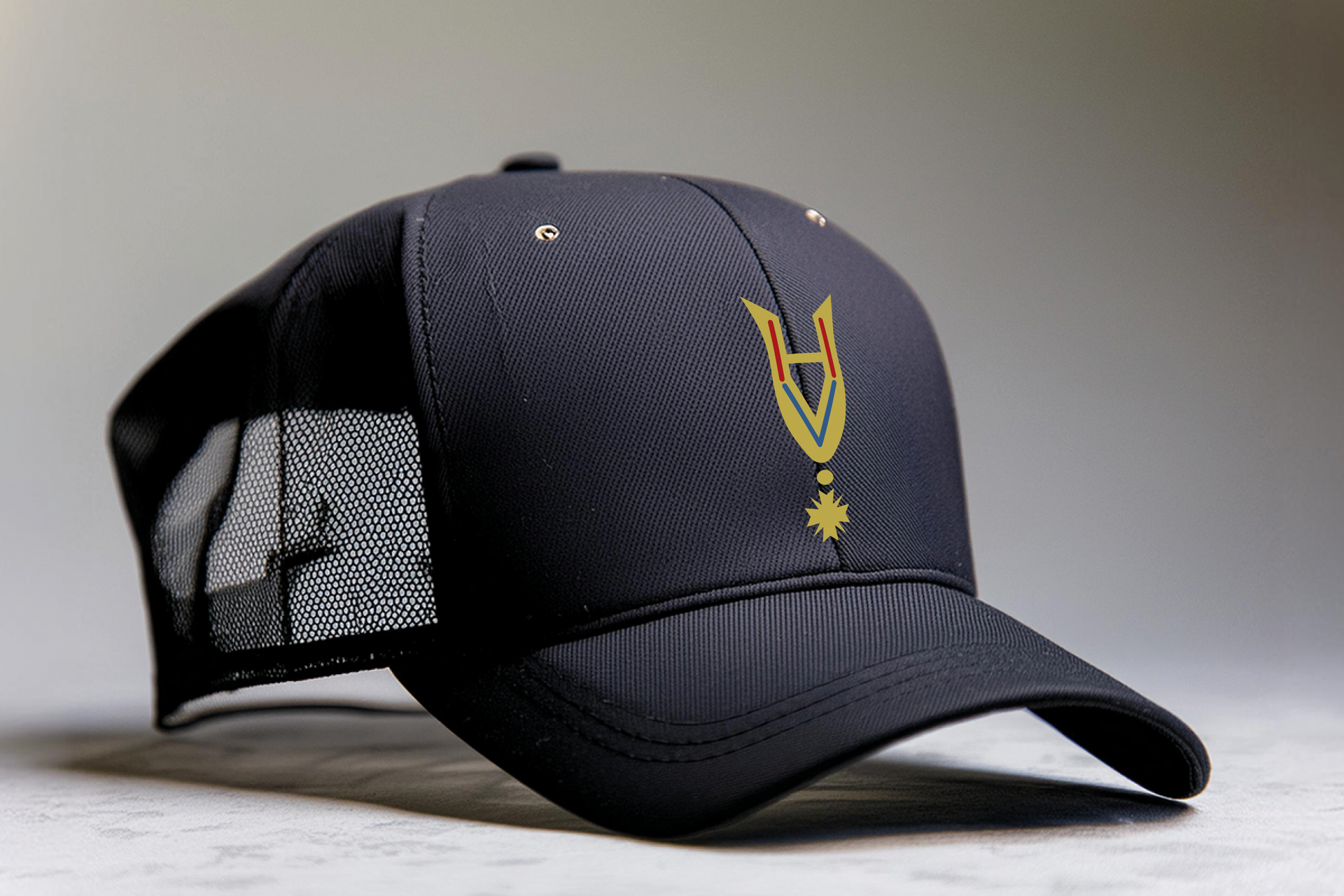 Zwarte cap met een goudgeborduurd medaille-embleem in het midden van de voorkant.
