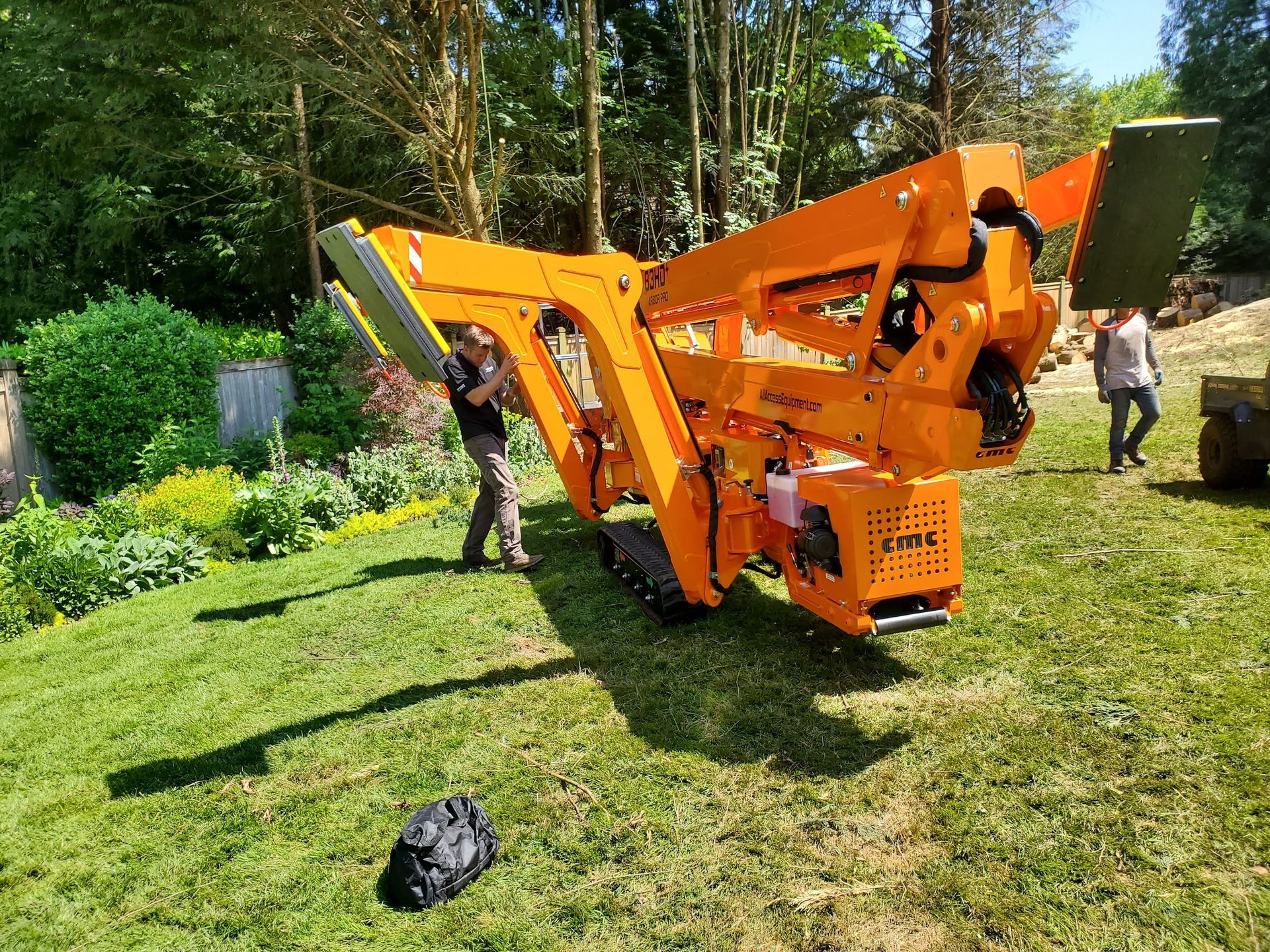 Orange tree chipper on tracks in a grassy yard; two people nearby.