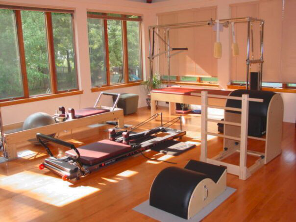 Pilates studio with wooden equipment, natural light, and a variety of exercise apparatus.
