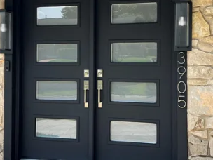 Black front door with four horizontal windows and silver handles beside stone wall, house number 3905 on the right
