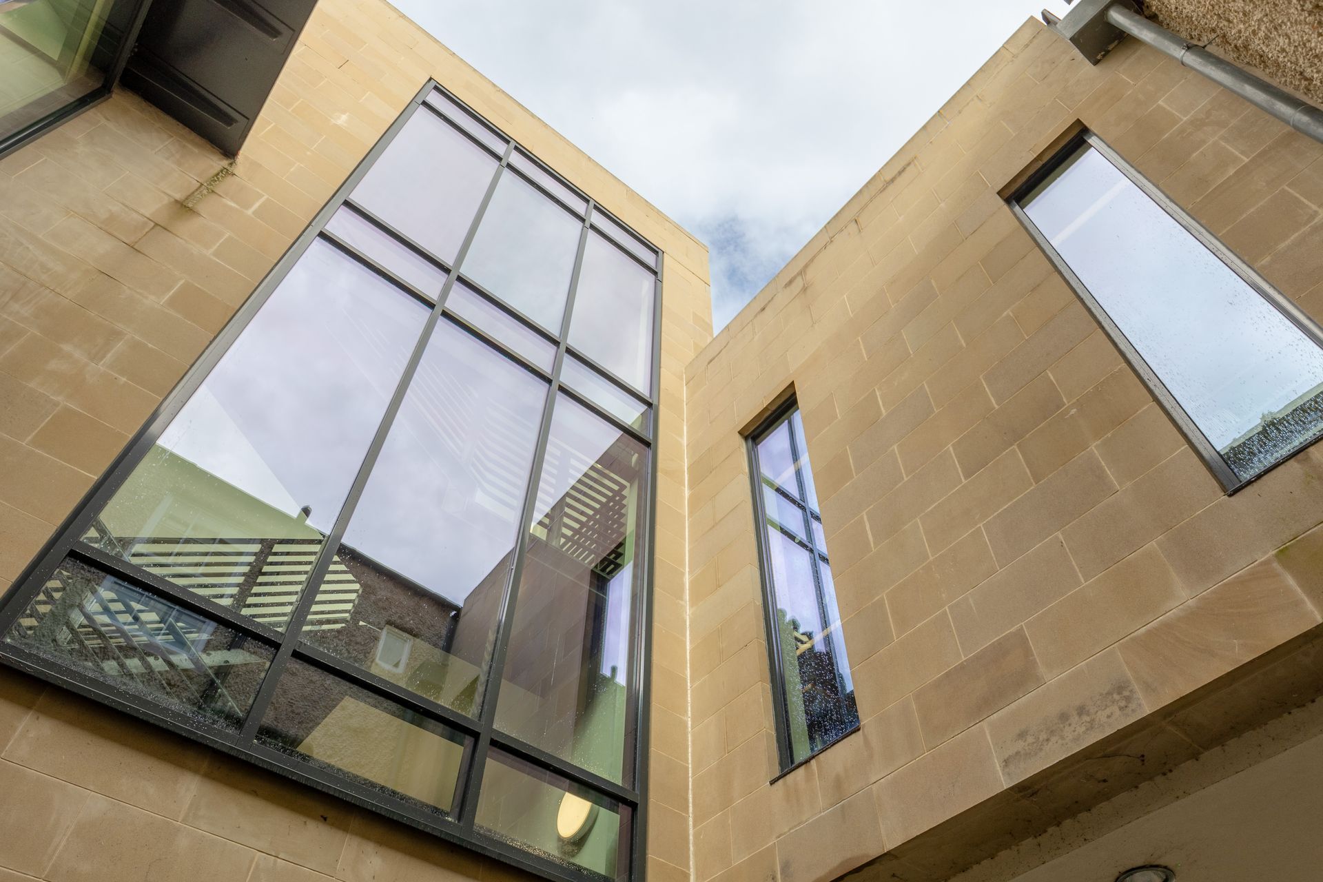 Modern tan buildings with large glass windows viewed from below against the sky