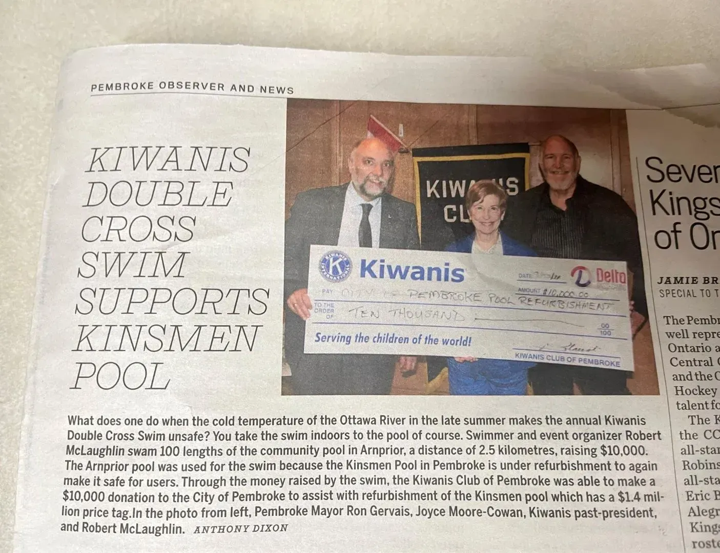 Newspaper article about Kiwanis, with people holding a large check in front of a banner.