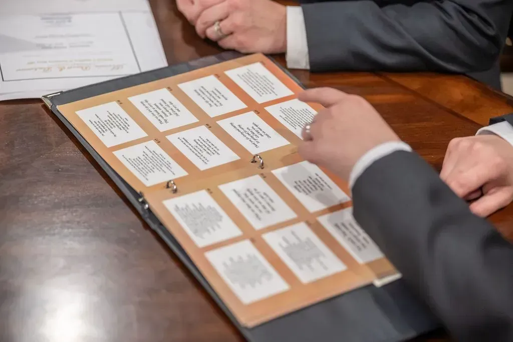 Hands reviewing a board game score sheet with small cards on a wooden table