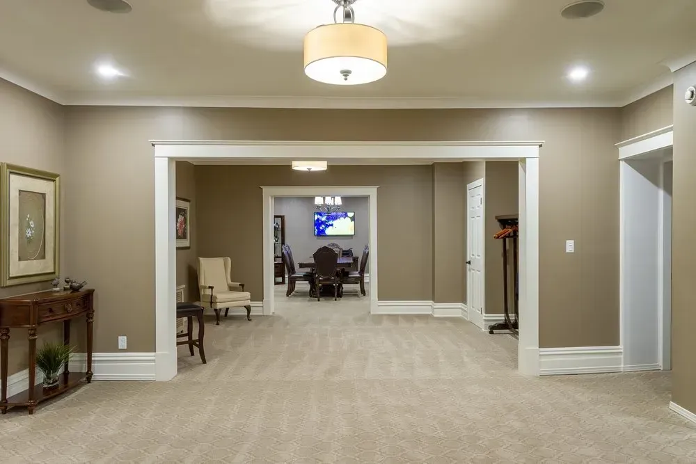 Spacious beige hallway with carpet, white trim, and a view into a meeting room at the far end