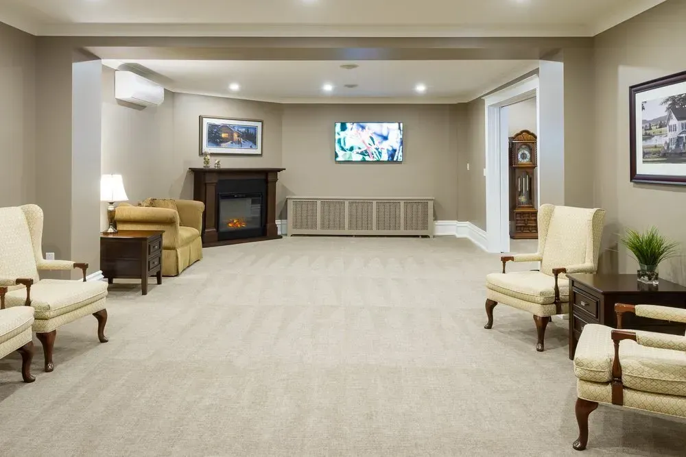 Quiet waiting room with beige chairs, fireplace, wall art, and a TV on the far wall