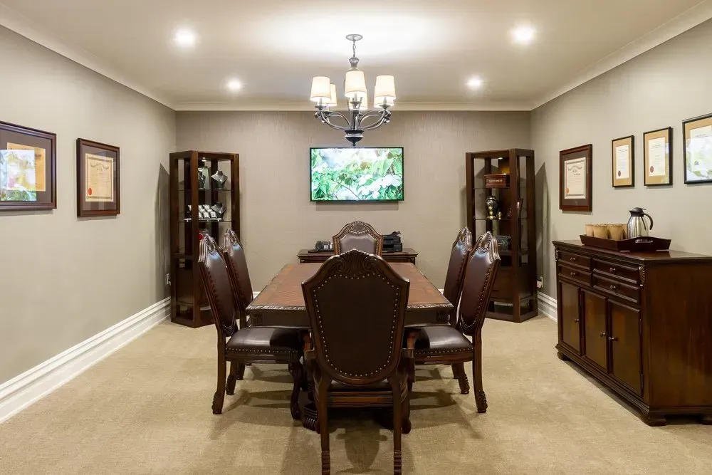 Elegant dining room with long wooden table, upholstered chairs, chandelier, and wall art on beige walls