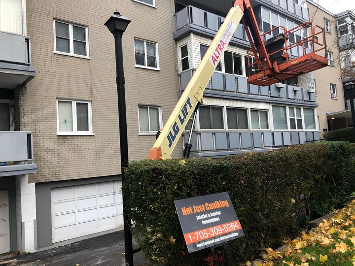 A crane is sitting on top of a building next to a sign.