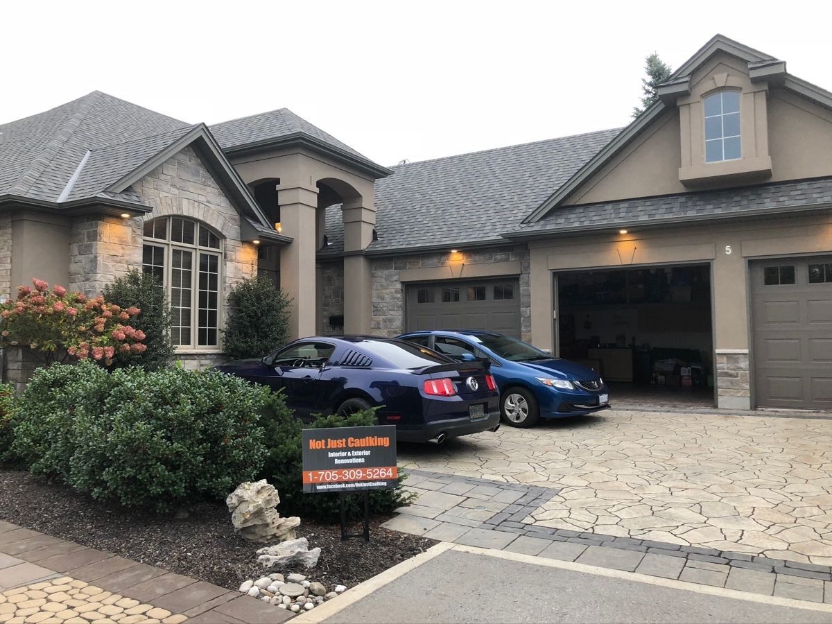 Suburban house with three cars in the driveway and a real estate sign by the front walk
