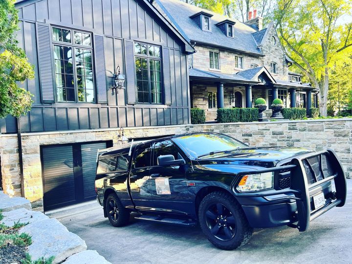 A black truck is parked in front of a large house.