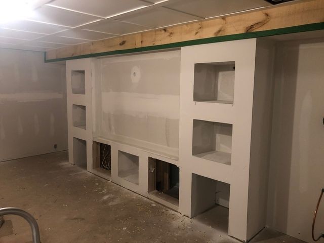 Interior view of drywall entertainment center with recessed shelving and built-in storage units in a basement.