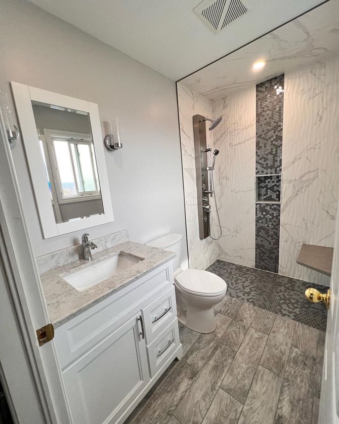 A bathroom with a toilet , sink , mirror and walk in shower.