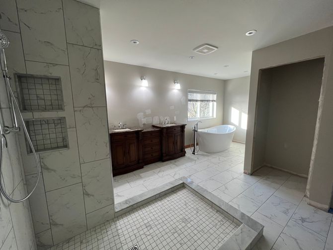 A bathroom with two sinks , a tub , and a walk in shower.