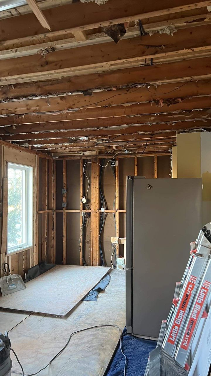 A kitchen under construction with a refrigerator and a ladder.
