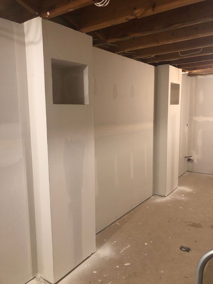 A basement with drywall walls and a wooden ceiling.