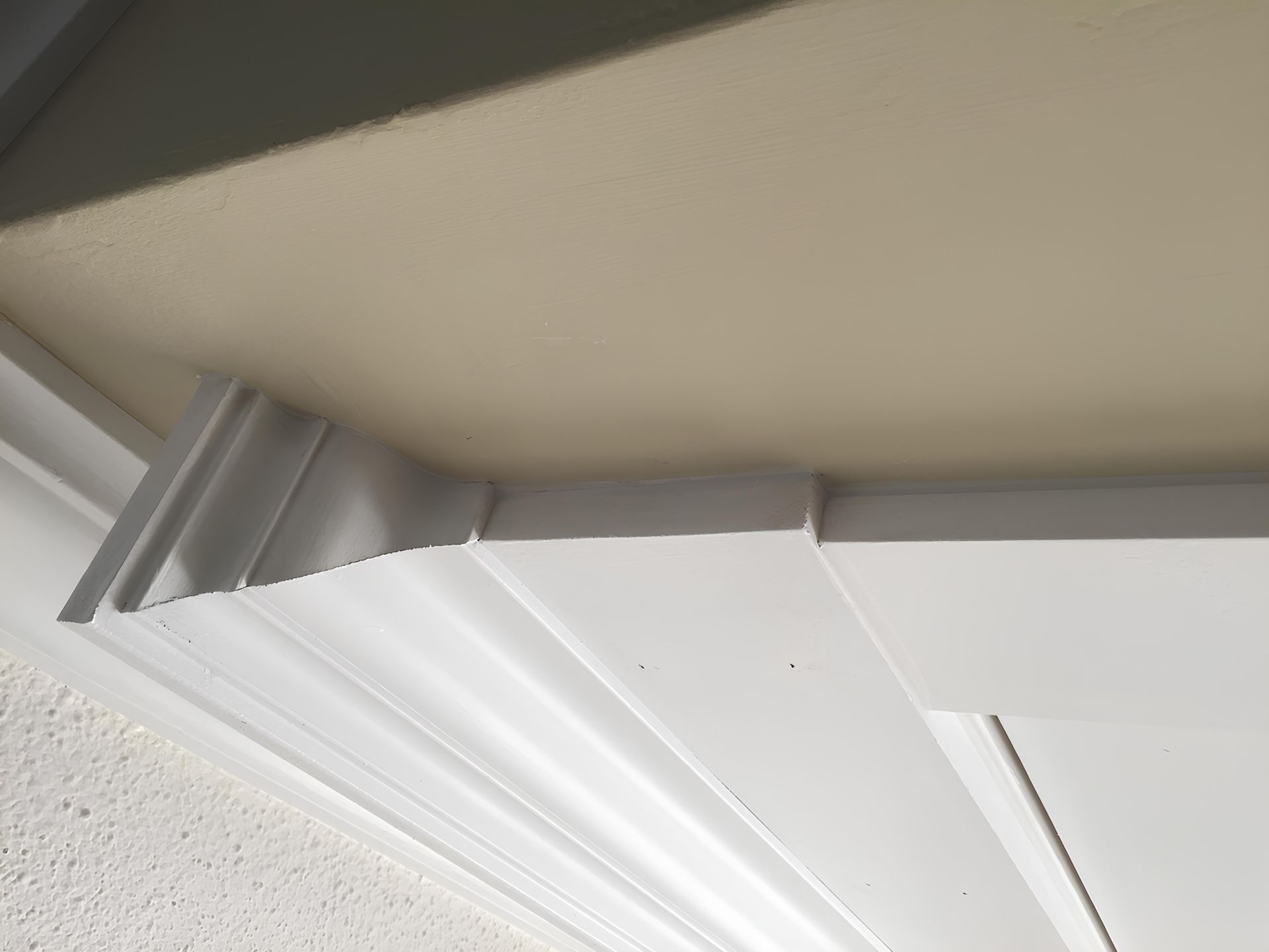 White crown molding against a beige ceiling, with a visible angled corner.