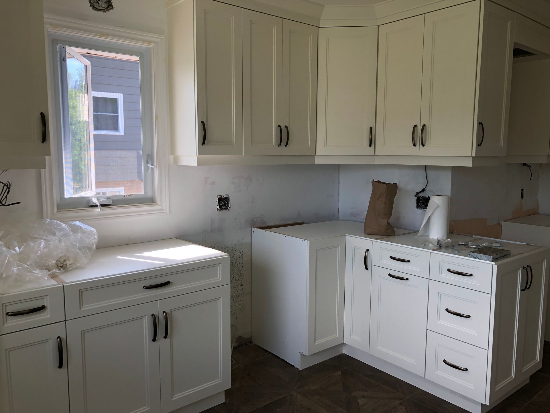 White kitchen cabinets being installed next to a window.
