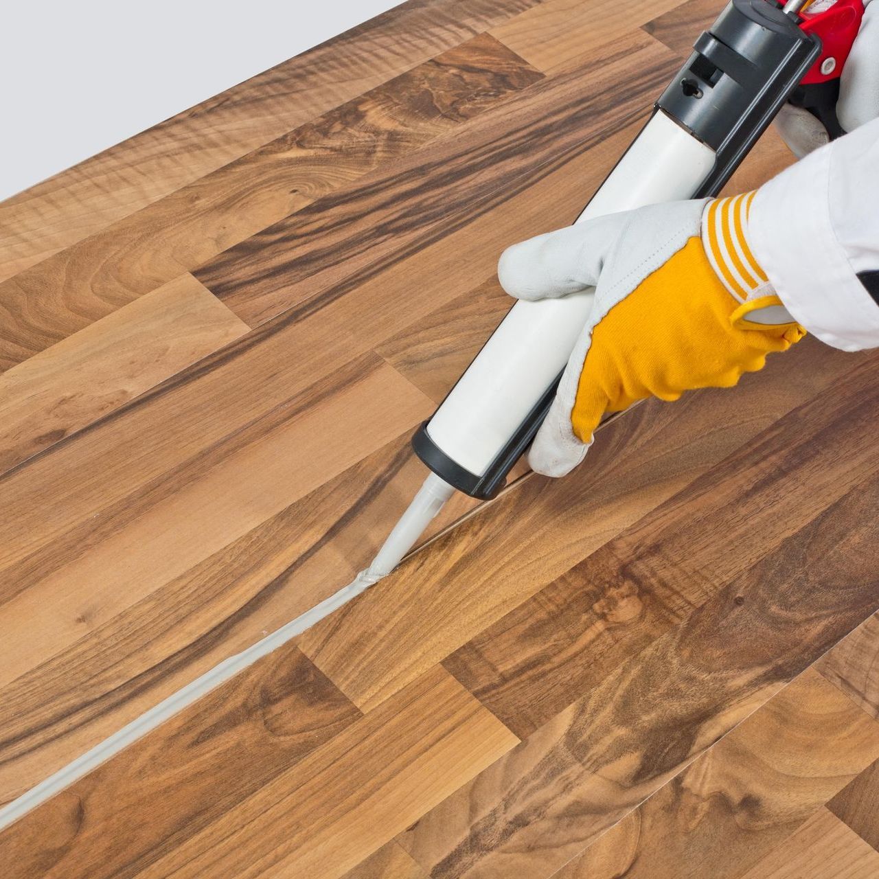 A person is applying sealant to a wooden floor
