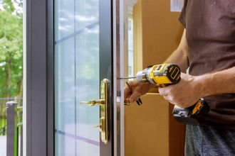 A man is fixing a door with a drill.