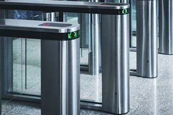 Rows of stainless steel turnstiles in a modern glass entrance lobby