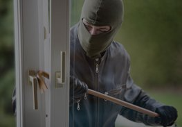 Masked burglar prying open a door with a crowbar