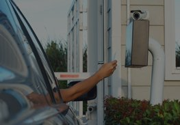 Arm reaching from a car toward a parking payment machine at a building entrance