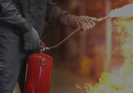 Person using a red fire extinguisher to spray flames indoors