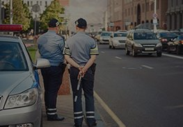 Two police officers standing on a city street beside parked cars