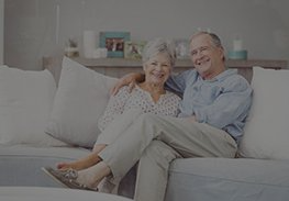 Smiling couple sitting together on a white sofa in a bright living room
