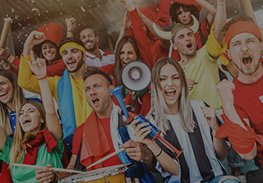 Crowd of cheering sports fans in colorful scarves, waving flags and chanting in stadium seats