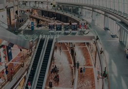 Aerial view of a modern shopping mall with escalators, curved walkways, and a few people below