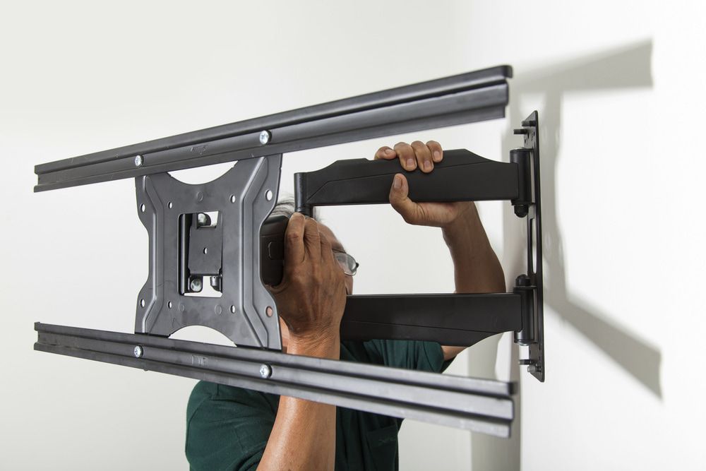 Man Installing a Black Tv Wall Mount — Flexicoms Communications in Ingham, QLD