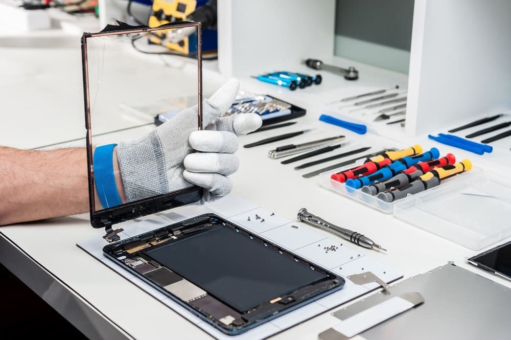 A Person Wearing a Glove Holds a Broken Tablet Screen — Flexicoms Communications in Innisfail, QLD 