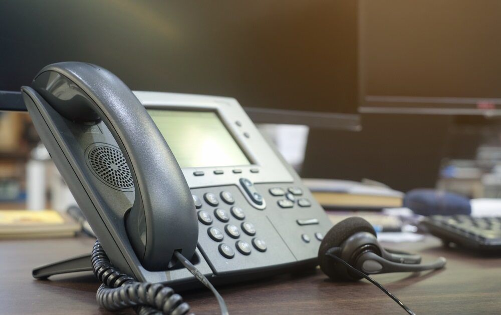 A Black Office Phone With a Headset Rests on a Desk — Flexicoms Communications in Ingham, QLD 